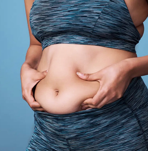Stock image of a woman without face , holding her stomach with both hands to show excess fat .