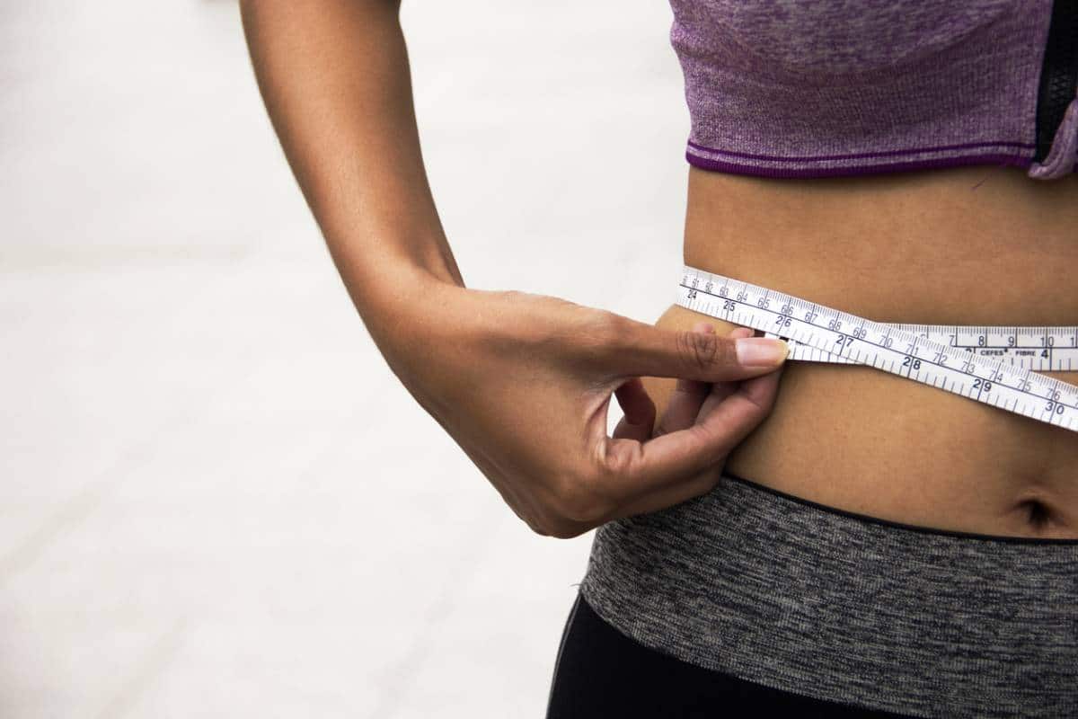 woman wrapping measuring tape around waist